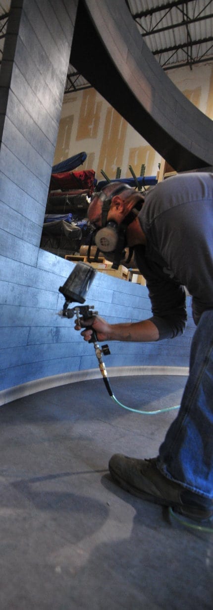 A Holt Environments employee sprays branded paint finish onto interactive digital display partition