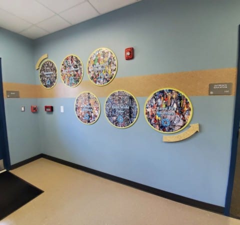 Custom printed vinyl color images applied to extruded wooden panels mounted onto wall in hallway of York County MRF
