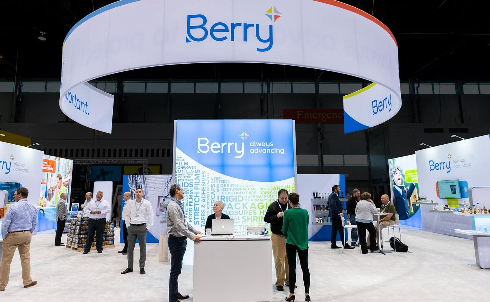 Trade show exhibit with reception desk and large circular cable-suspended ceiling overhead structure