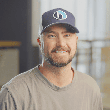 Smiling man wearing a cap in a modern workspace, representing Holt Experiential branding.
