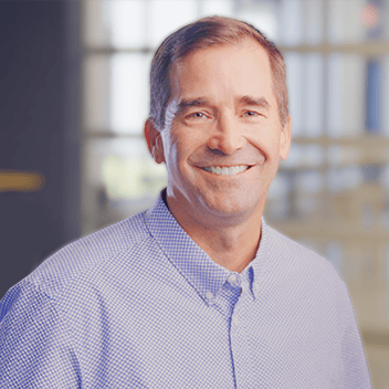 Professional corporate man smiling in modern office, lens-focused on business success and experiential marketing.