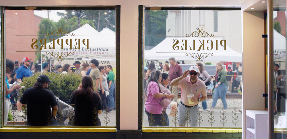 Visitor looking through the window of the Mount Olive Pickle Parlor.