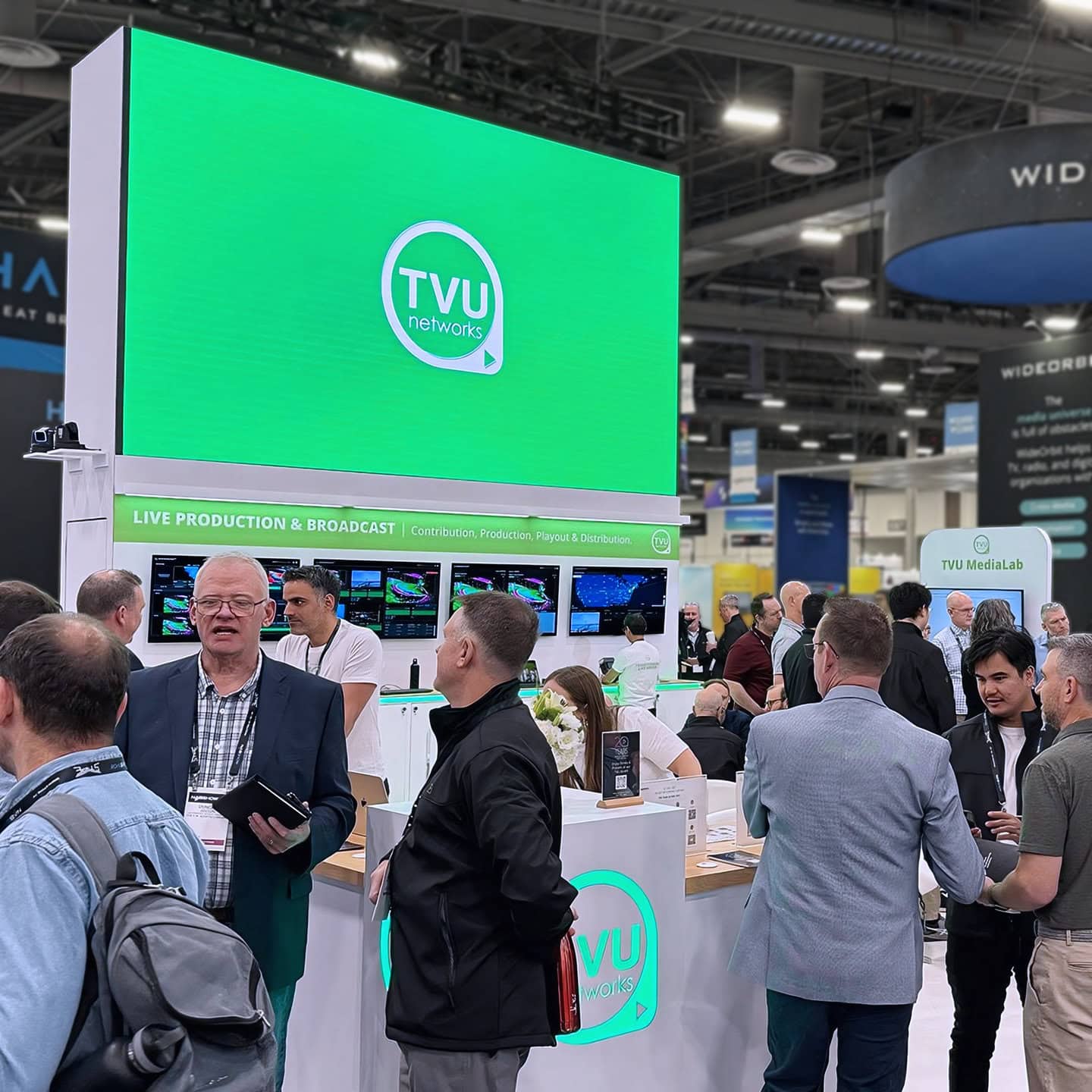 TVU Networks exhibit at NAB 2025 - crowd with green LED screen