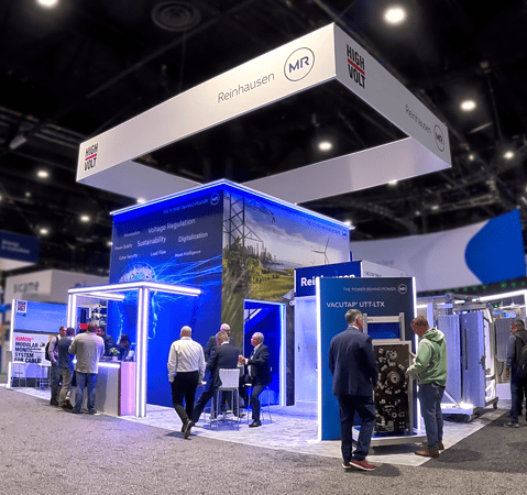 Wide view of Reinhausen's custom two-story exhibit at IEEE 2026 in Chicago with visitors exploring products and meeting with the sales team.